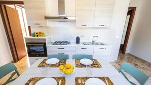 A modern kitchen with white cabinets, a gas stove, and a sink. - Cloe House - Mondello (Palermo)
