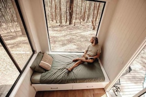 A room with a built-in window seat overlooking a forest.