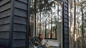 Una cabaña con un amplio ventanal con vistas a un bosque.