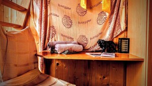 Una habitación acogedora con un banco de madera, una mesita con una lámpara y un cubo de basura.