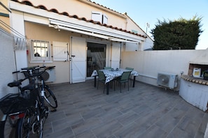 A patio with a table and chairs, a bicycle, and an air conditioning unit.