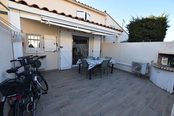 A patio with a table and chairs, a bicycle, and an air conditioning unit.