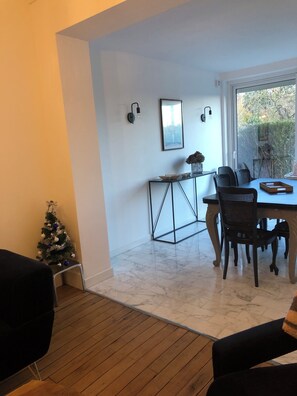 Uma área de refeições com mesa e cadeiras, uma pequena árvore de Natal e uma janela com vista para o verde.
