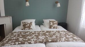 Een slaapkamer met een bed, twee wandlampen, een nachtkastje en een open haard.