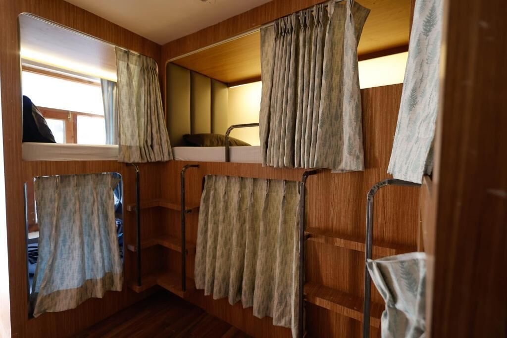 A compact, wooden interior with bunk beds, a mirror, and curtains.