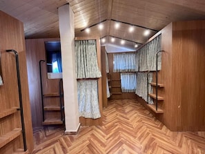 A room with wooden flooring, built-in shelving, and a staircase.