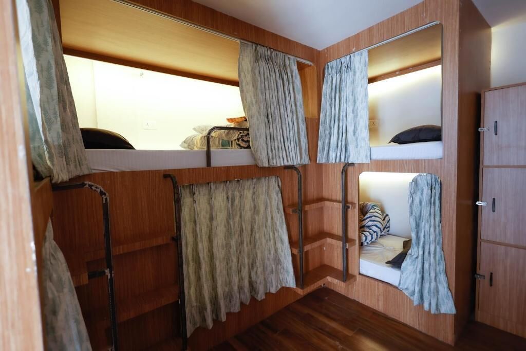 Een kleine kamer met een stapelbed, een spiegel en een houten garderobe.