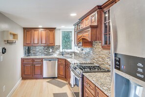 A modern kitchen with wooden cabinets, a stainless steel refrigerator, and a tiled backsplash.