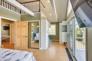 A spacious bedroom with a large bed, a wooden door, a closet, and a view of the outdoors.