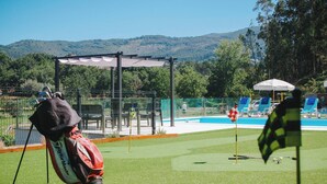 A golf course with a netted area, a pool, and a view of hills. - Sandoco House - Pitch&putt Golf - Pool & Nature (Ponte de Lima)