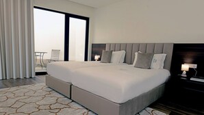 A modern hotel room with a large bed, a view to the outside, a small table and chair, and a nightstand with a lamp. - Sandoco House - Pitch&putt Golf - Pool & Nature (Ponte de Lima)