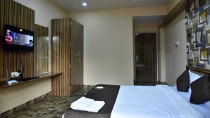 Ein Hotelzimmer mit Bett, Fernseher an der Wand, Kleiderschrank und Spiegel.