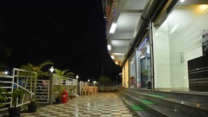 Ein Hotel mit Eingangsbereich, Schachbrettboden, Außenbereich mit Sitzgelegenheiten und einer Glasfassade.