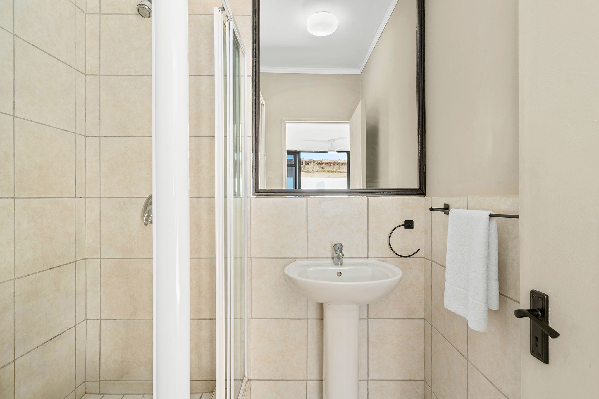 Een moderne badkamer met een douchecabine van glas, een wit wastafelmeubel en een handdoekrek.