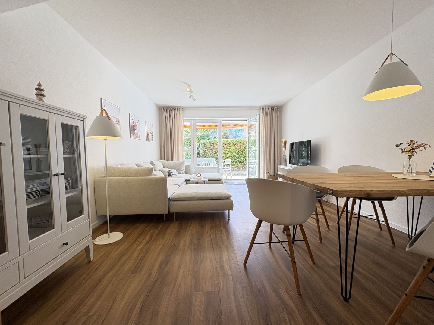 Una sala de estar moderna con un sofá, mesa de comedor, sillas, un mueble aparador y un televisor.