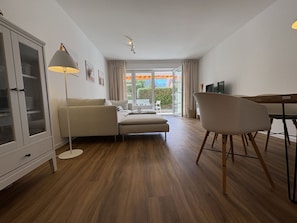 Un salon moderne comprenant un canapé, une table à manger, un téléviseur et un meuble.
