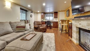 A cozy living room with a sofa, a fireplace, and a kitchen area in the background. - 1 Mi to Shaver Lake! Family & Couples Condo (Shaver Lake)