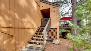 A wooden cabin with a staircase leading to a deck, surrounded by trees and a red umbrella. - 1 Mi to Shaver Lake! Family & Couples Condo (Shaver Lake)