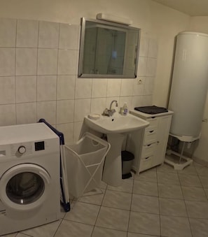 Un baño pequeño con lavadora, lavabo con espejo e inodoro.