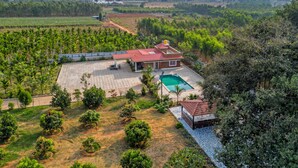Una casa con techo rojo, piscina y jardín.