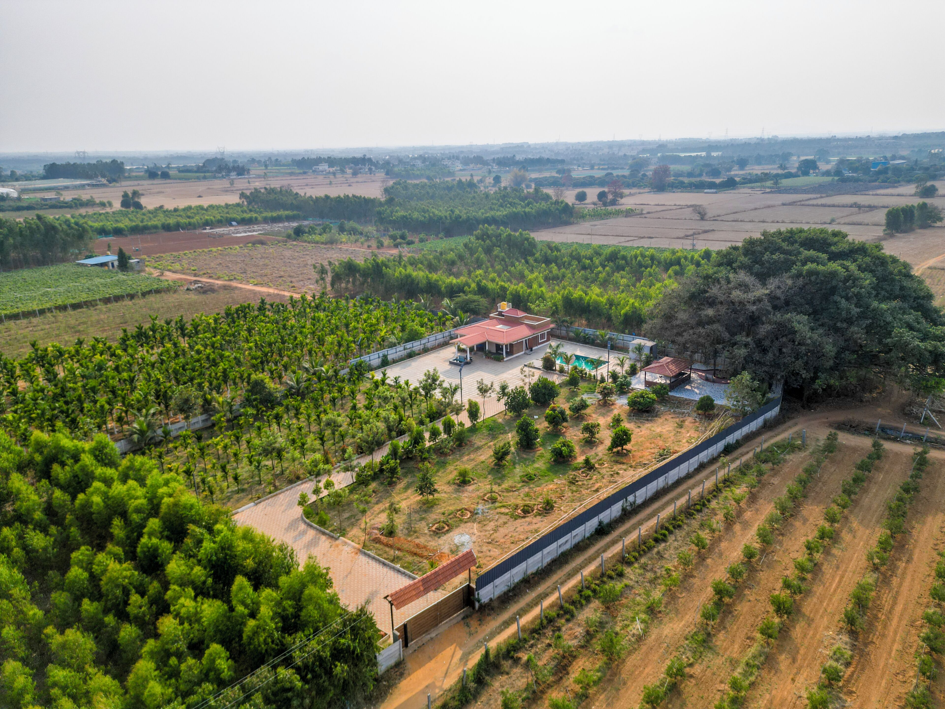 An aerial view of a property with a large house, a swimming pool, and surrounding agricultural fields.