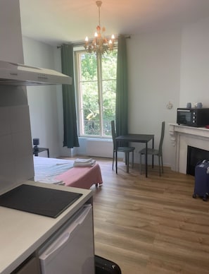 Cozinha compacta com micro-ondas, uma mesa pequena para refeições e uma janela com cortinas.
