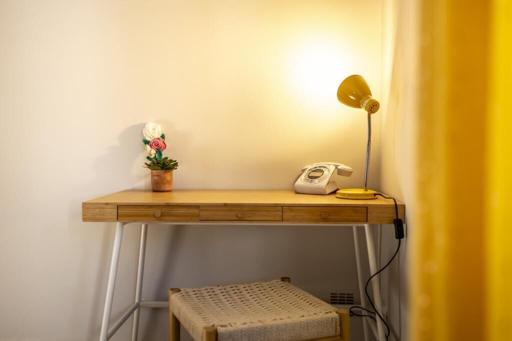 A wooden desk with a lamp, a telephone, and a potted plant.