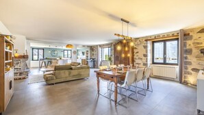 Amplia sala de estar con mesa de comedor, sofá y cocina al fondo.