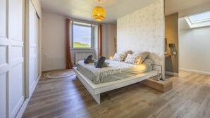 Un dormitorio con cama, ventana, lámpara en el techo y una puerta.