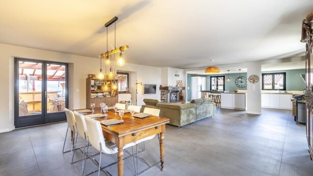 Un amplio espacio de sala con una mesa de comedor, sillas y una cocina al fondo.