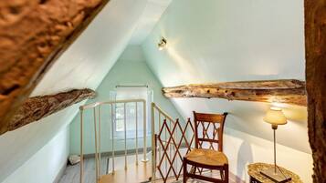 Une pièce avec un plafond en bois, une chaise, une lampe et un escalier.