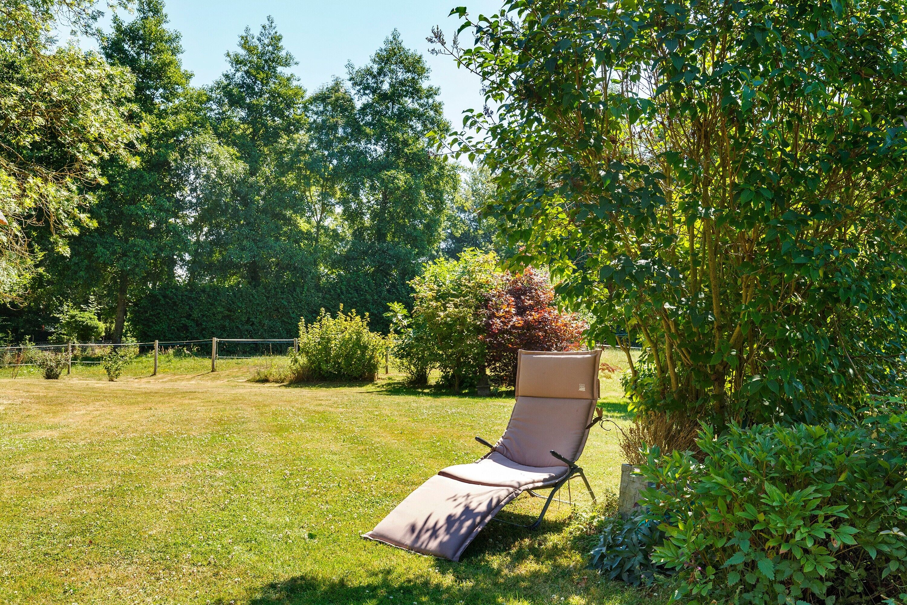 Un jardin avec une pelouse, une clôture en bois et un seul transat.