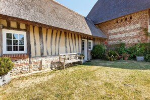 A traditional building with a thatched roof, a wooden bench, and a stone wall. - Holiday Home 'La Petite Chaumière' with Shared Garden (Sainte-Foy)