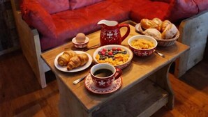 Et hyggeligt rum med en træsofa, et bord med morgenmad og stenvægge.