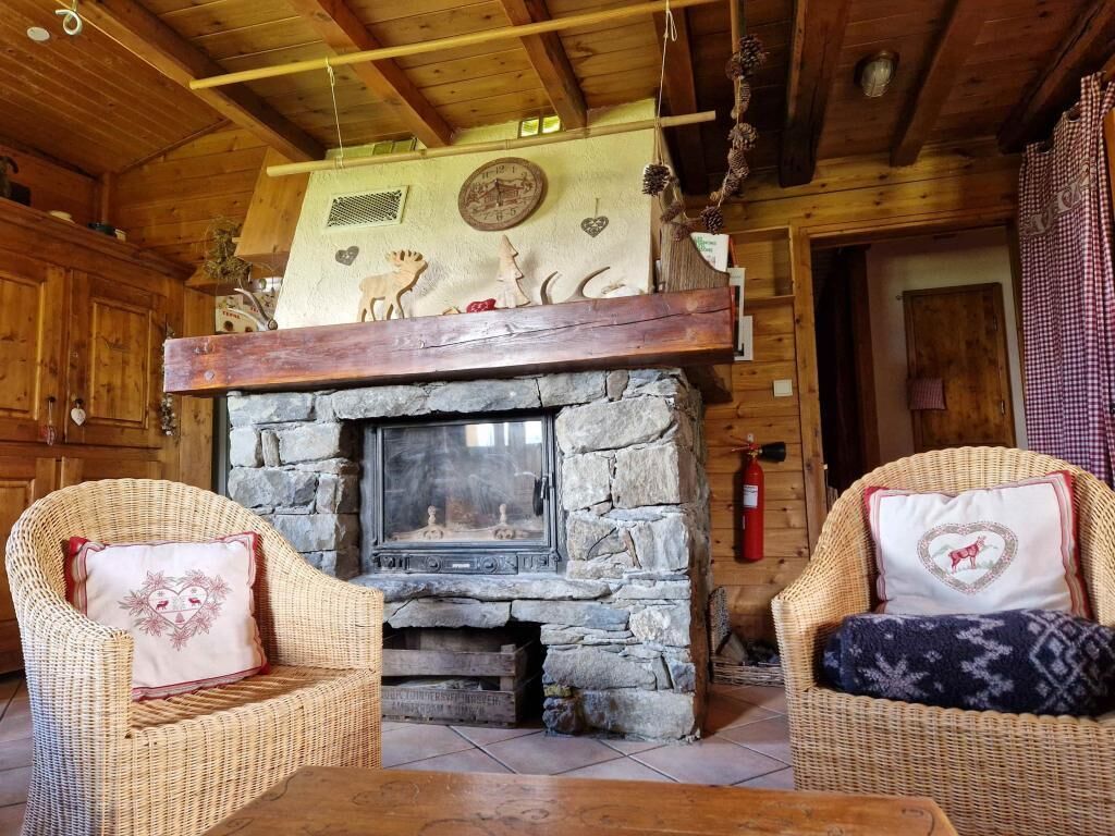 Een gezellig chaletinterieur met een stenen openhaard, rieten meubels en houten balken.