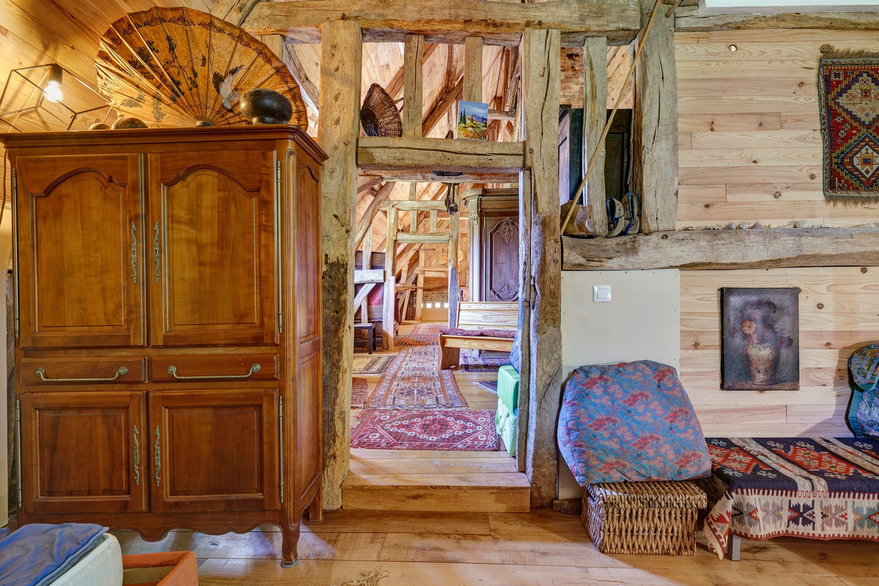 Un intérieur rustique avec un meuble en bois, un banc en osier et un tapis à motifs.