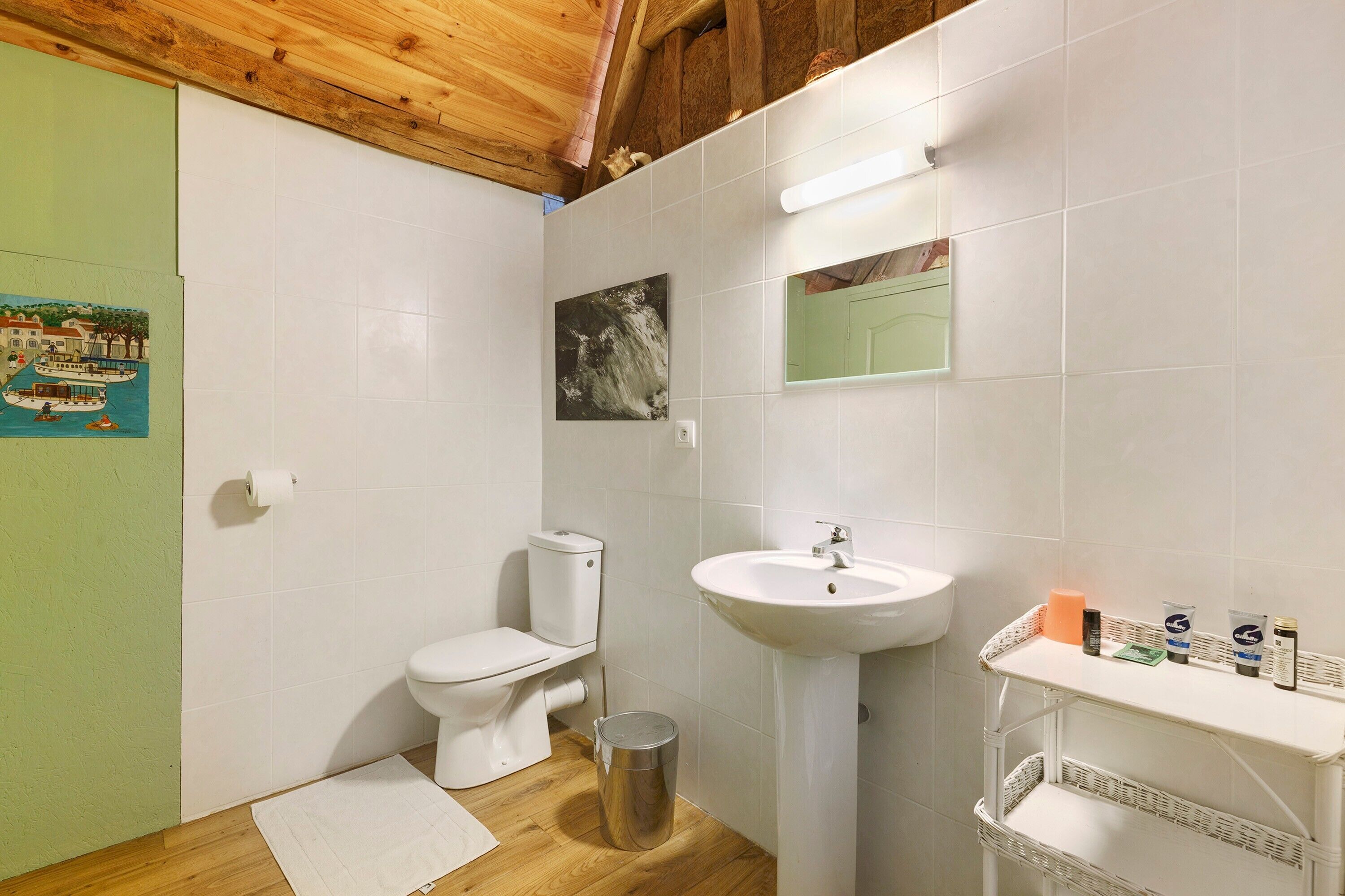 Une salle de bain avec des toilettes, un lavabo et une petite poubelle.