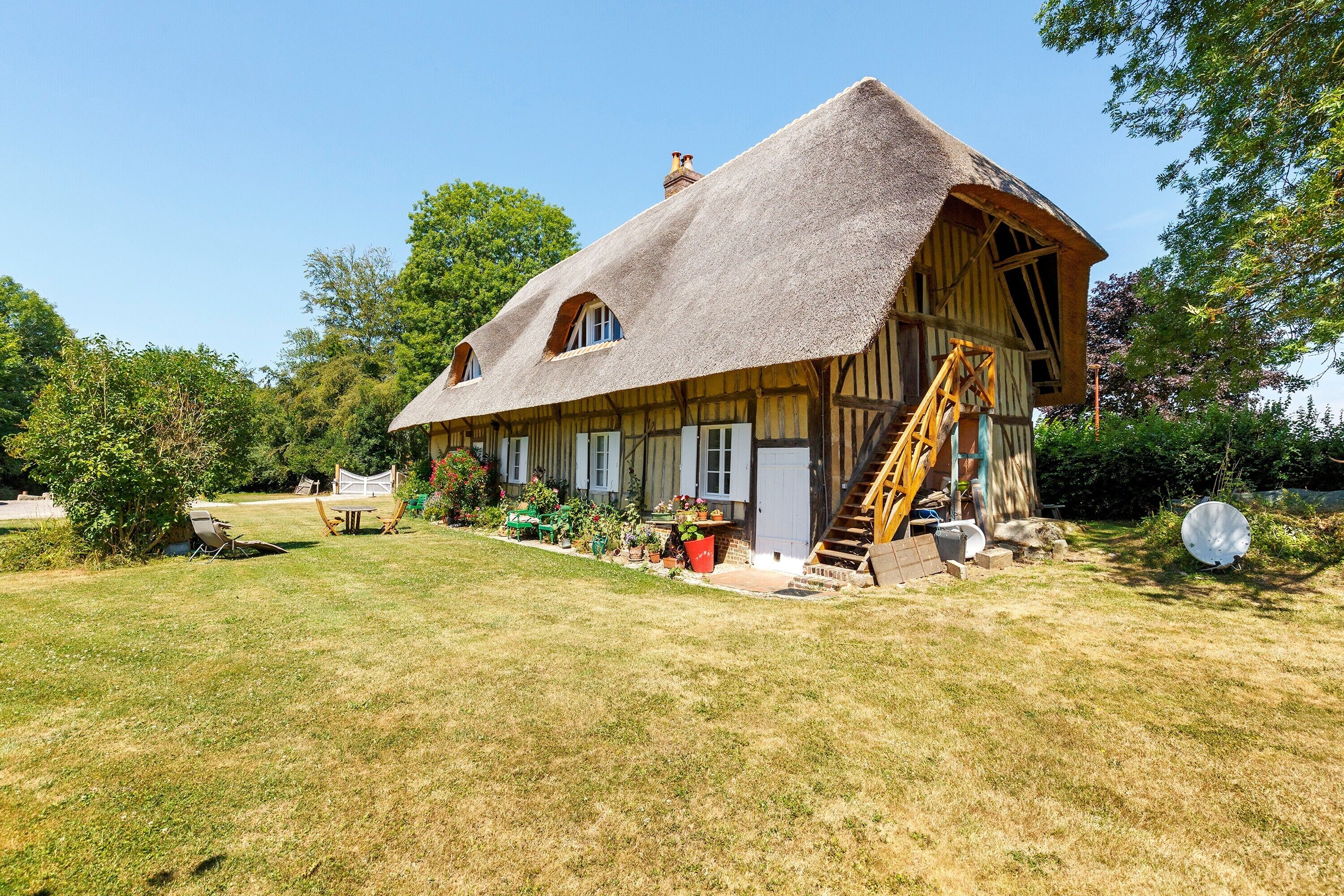 Ein traditionelles Haus mit einem Strohdach und einer Holztreppe zum Eingang.