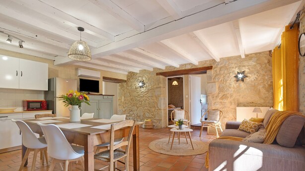Amplia sala de estar con una mesa de comedor, sillas, un sofá y una cocina al fondo.