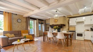 Una sala de estar con sofá, mesa de centro, comedor, sillas y una zona de cocina con armarios y electrodomésticos.