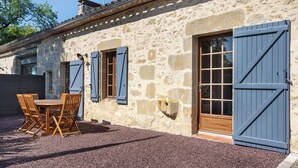 Un edificio de piedra con una mesa y sillas de madera, una puerta azul y una ventana.