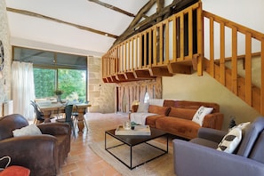 Ein geräumiger Wohnbereich mit einer Holztreppe, einem Esstisch und einer Couch.
