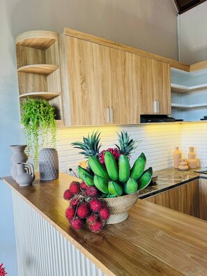 Eine Küche mit Holzschränken, einer Marmorarbeitsplatte und verschiedenen Früchten und Pflanzen.