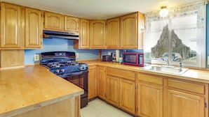 A kitchen with wooden cabinets, a stove, a microwave, and a sink. - Near I-95 & Rhode Island Border! Pet-Friendly Home (Attleboro)