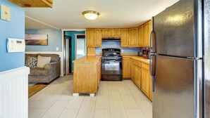 A kitchen with wooden cabinets, a black refrigerator, a stove, and a microwave. - Near I-95 & Rhode Island Border! Pet-Friendly Home (Attleboro)