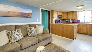 A living room with a sofa, a kitchen with wooden cabinets, a microwave, and a coffee maker. - Near I-95 & Rhode Island Border! Pet-Friendly Home (Attleboro)