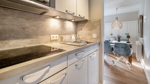Et moderne køkken med en stor ø, rustfrie stålapparater og et spiseområde med bord og stole.