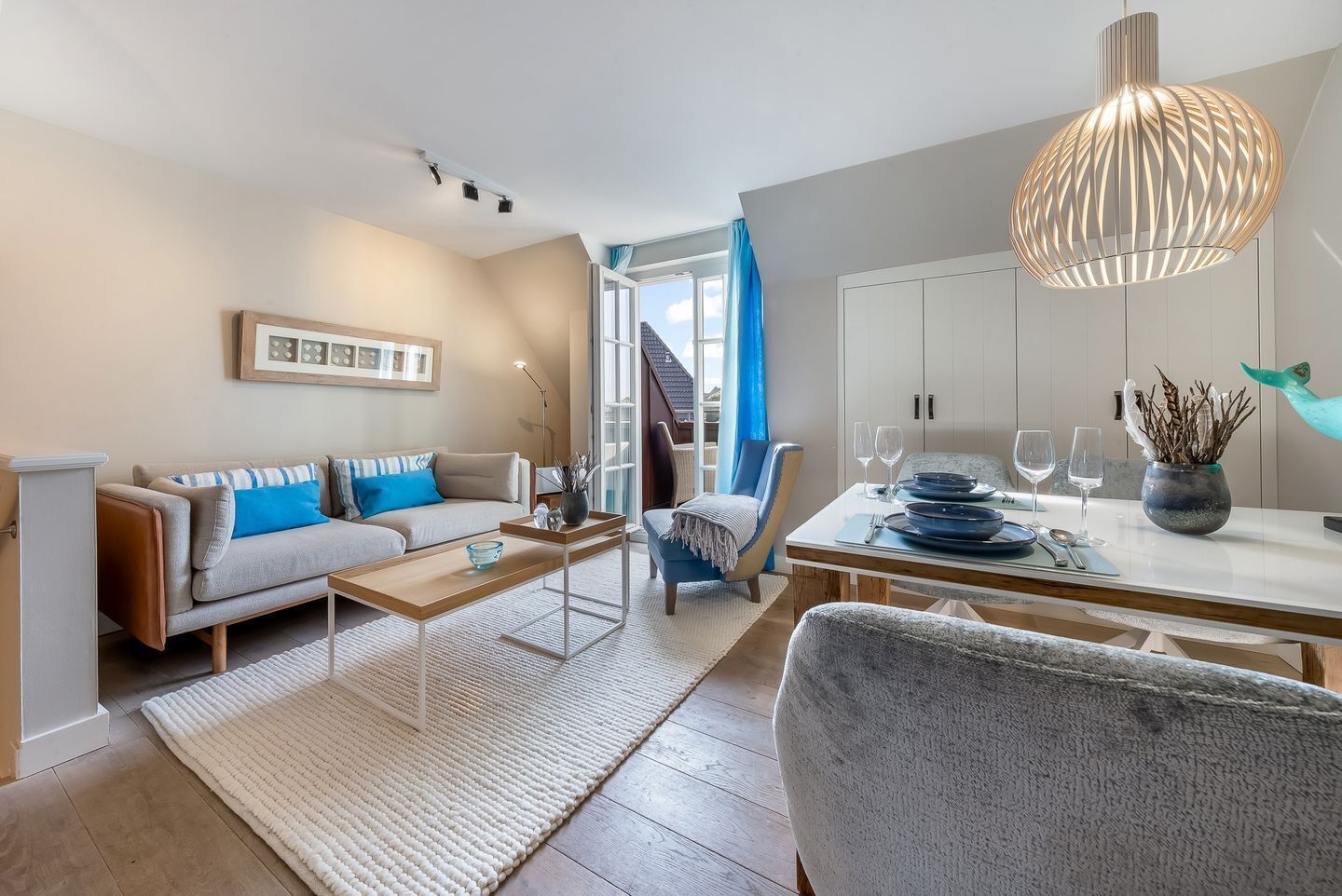 A modern living room with a sofa, coffee table, and dining area with a table set for two.