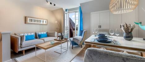 A modern living room with a sofa, coffee table, and dining area with a table set for two.