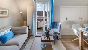 En moderne stue med sofa, sofabord og spiseplads med stol og bord.